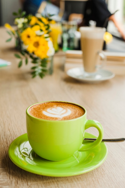 Tasty latte coffee with latte art in green cup at restaurant