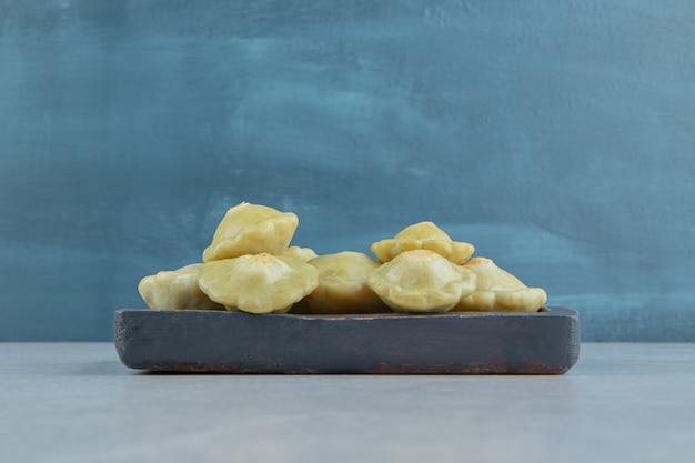 Tasty mini squash in the wooden plate on the marble surface