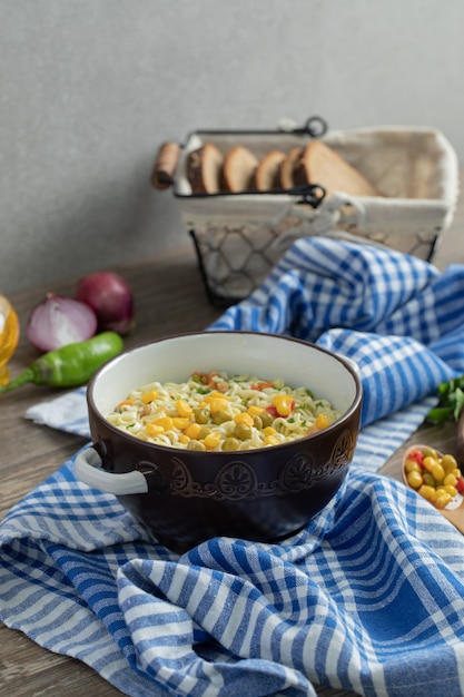 Free photo tasty noodles in bowl and basket of bread on wooden table