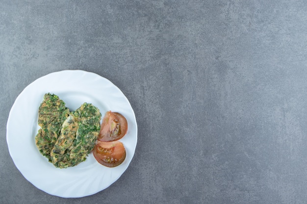 Tasty omelette with greens on white plate.