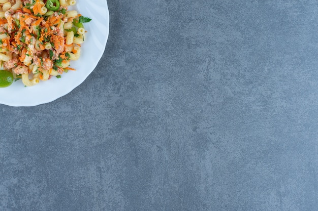 Tasty pasta with chopped vegetables on white plate. 