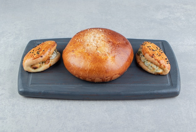 Tasty pastries with cheese and bun on black board. 