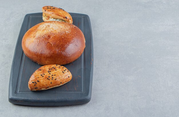 Tasty pastries with cheese and bun on black board.