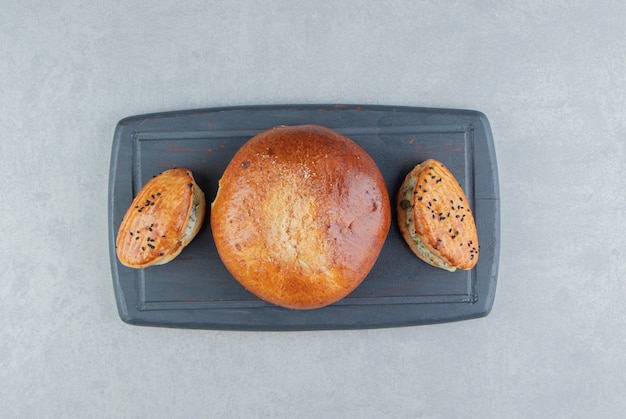 Tasty pastries with cheese and bun on black board.