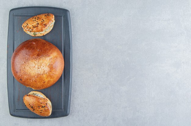 Tasty pastries with cheese and bun on black board.