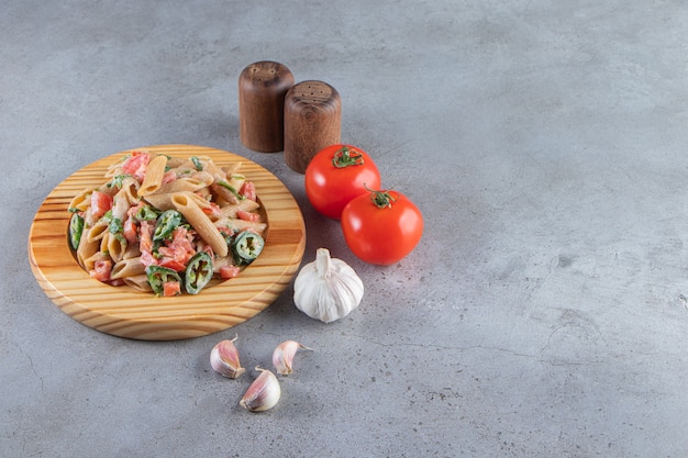 Free photo tasty penne pasta with fresh chopped vegetables on wooden plate.