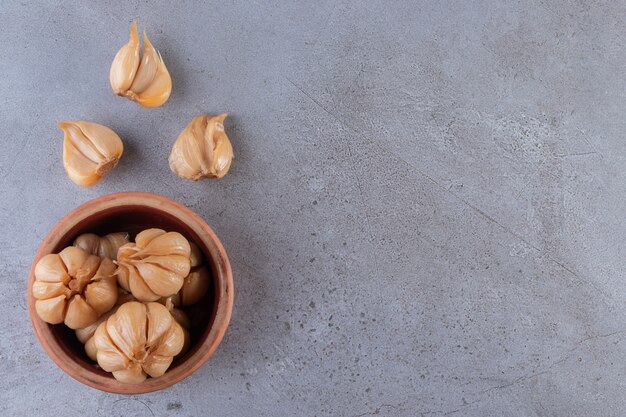 Tasty pickled garlic in the bowl placed on stone table.