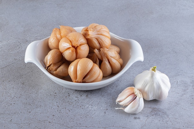 Tasty pickled garlic placed on a stone surface.