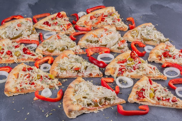 Free photo tasty pizza slices on blue with onion rings and pepper.