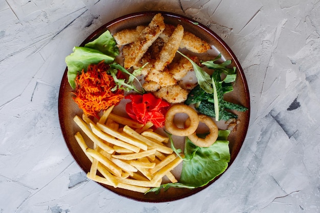 Free photo tasty restaurant appetizers for big company including goldy chicken nuggets fried potatoes green salad leaves and fresh cucumbers standing on white table looking delicious mouthwatering