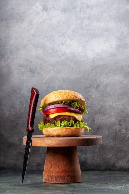 Tasty sandwich and red fork on wooden board on dark mix color surface with free space