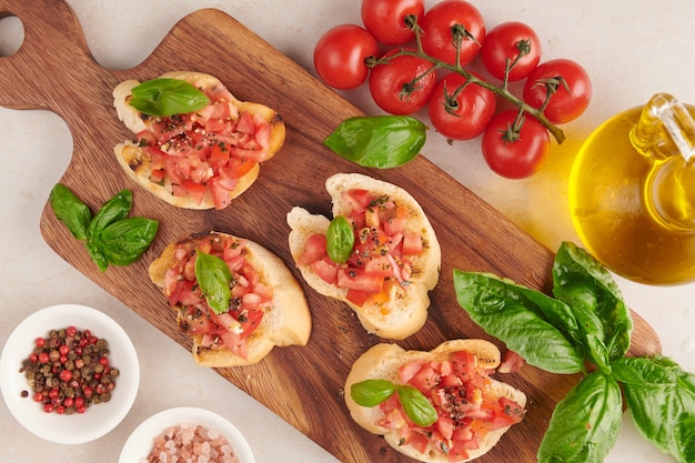 Free Photo tasty savory tomato italian appetizers, or bruschetta, on slices of toasted baguette garnished with basil, vegetables, herbs on grilled or toasted crusty ciabatta bread.