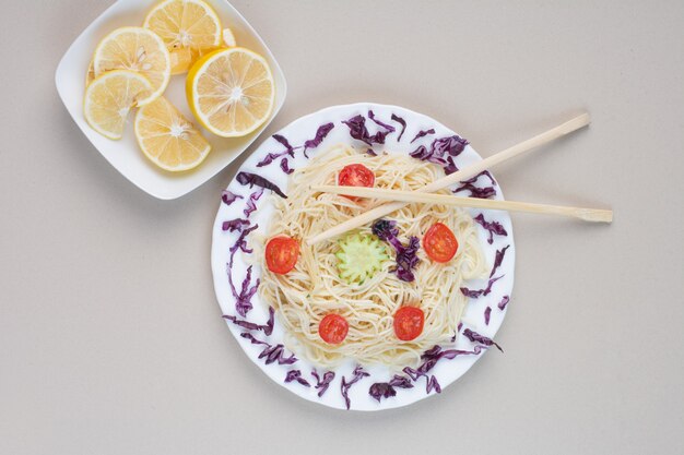 Tasty spaghetti and lemon slices on white surface