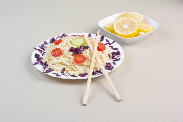 Tasty spaghetti and lemon slices on white surface