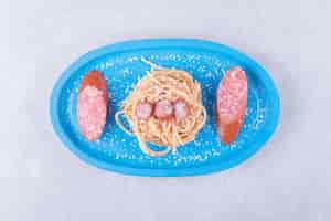 Free photo tasty spaghetti with sausages on blue plate.