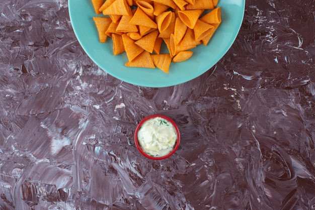 Free Photo tasty spicy chips on a plate next to yogurt, on the marble table.