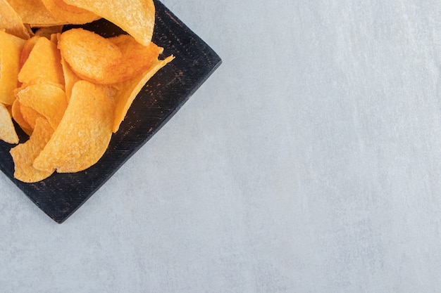 Free Photo tasty spicy potato chips on black cutting board.