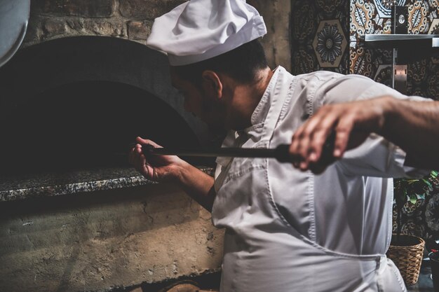 Tasty stonebaked pizza is ready and italian chef is removing it from oven.