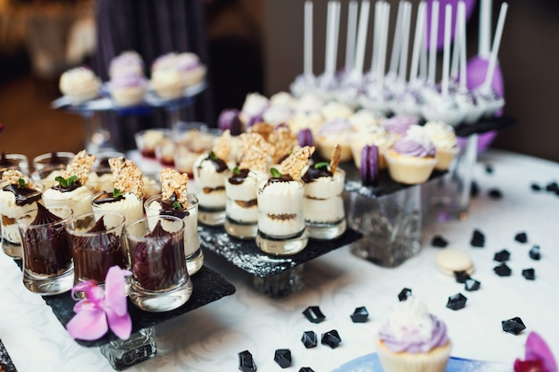 Free photo tasty sweets covered with violet and white glaze served on black