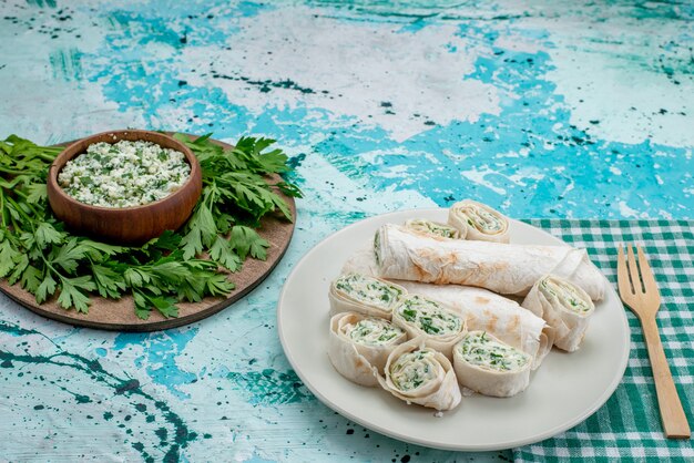 tasty vegetable rolls whole and sliced with greens and salad on blue desk