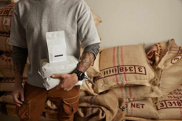 Free Photo tattooed barista holds blank package bags with freshly baked coffee beans ready for sale and delivery