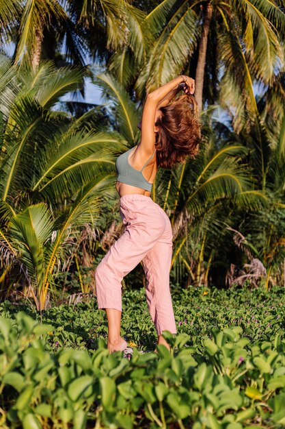 tattooed caucasian woman in pink pants and green trendy crop top