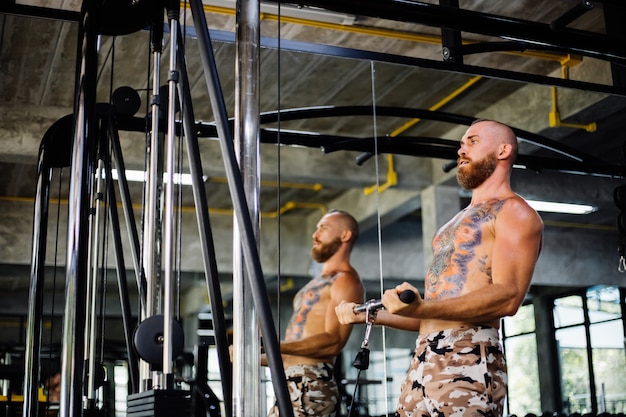 Tattooed fit man doing exercise at the gym