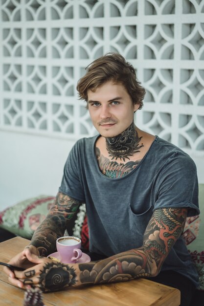 tattooed man drinking coffee in a cafe