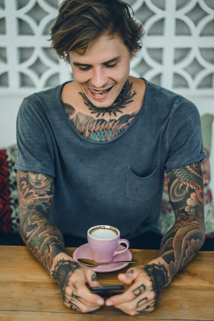 tattooed man drinking coffee in a cafe