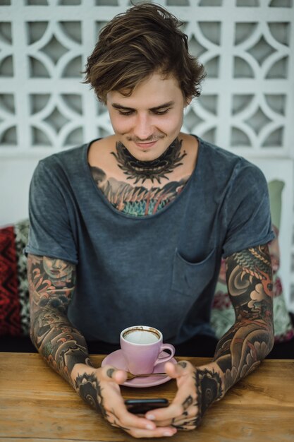 tattooed man drinking coffee in a cafe