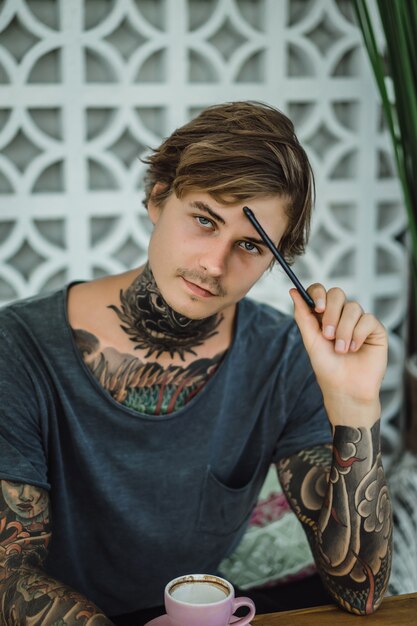 tattooed man drinking coffee in a cafe