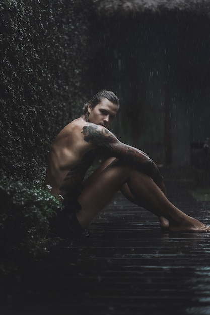 tattooed man posing in the rain