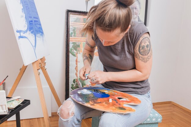 Tattooed woman mixing paints on palette