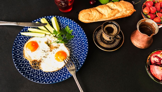 Tea, bread and fried omelette with slices of cucumber on blue plate