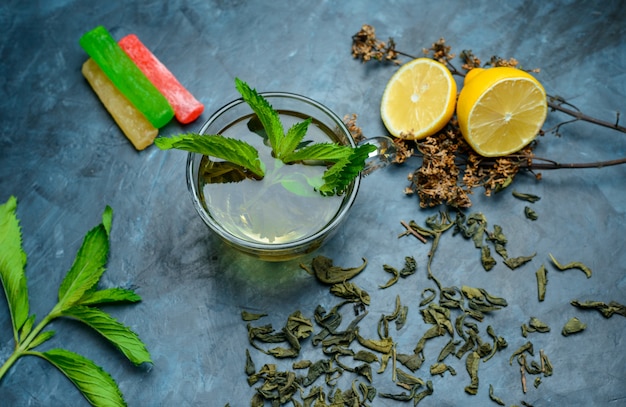 Free Photo tea in a cup with mint, dried herbs, lemon, sweeties flat lay on a dark blue surface