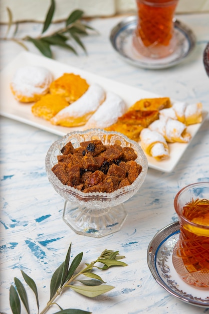 Tea set with varieties of traditional nuts, lemon, confiture and sweets served on white tablecloth