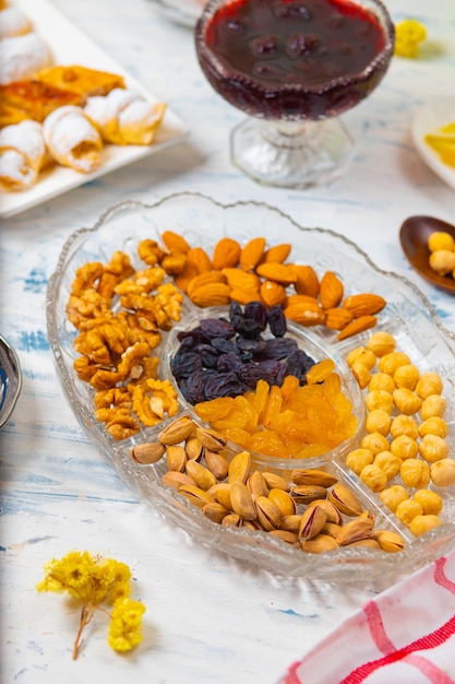 Tea set with varieties of traditional nuts, lemon, confiture and sweets served on white tablecloth