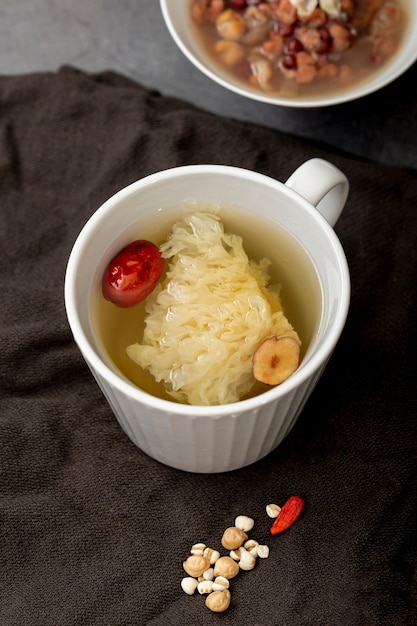 Tea in a white cup and a bowl with soup on a grey cloth