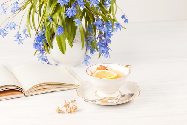 Tea with lemon and bouquet of  blue primroses on the table