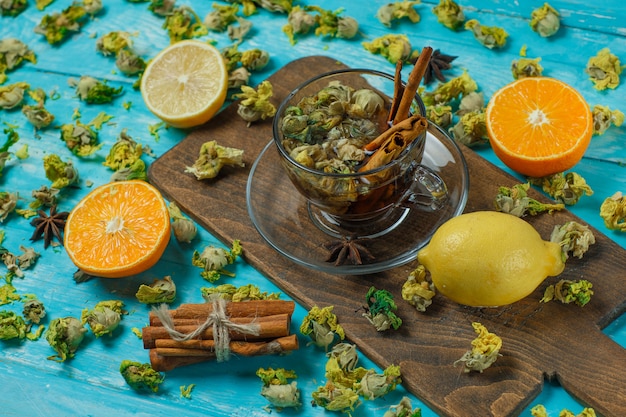 Free Photo tea with spices, orange, lemon, dried herbs in a mug on blue and cutting board