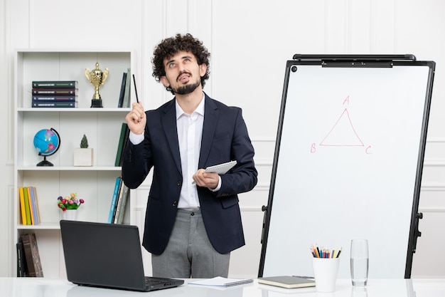 Teacher brunette instructor with computer in suit and whiteboard in classroom looking up