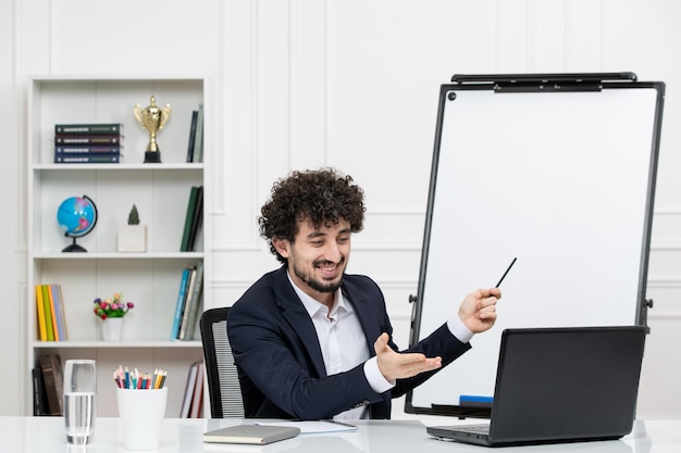 Teacher brunette instructor with computer in suit and whiteboard in classroom smiling