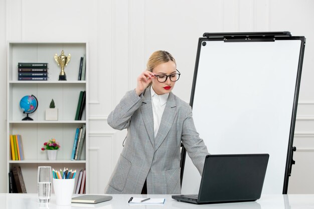 Teacher cute instructor in suit in classrom with computer and whiteboard looking at screen