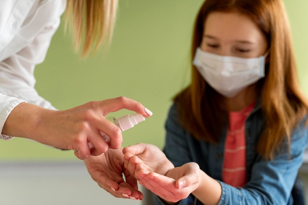 Teacher disinfecting child's hands in class