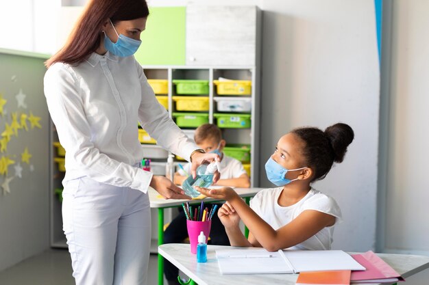 Teacher disinfecting children's hands