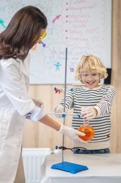 Teacher helping boy putting flask on tripod