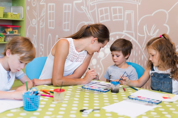 Teacher helping kid paint