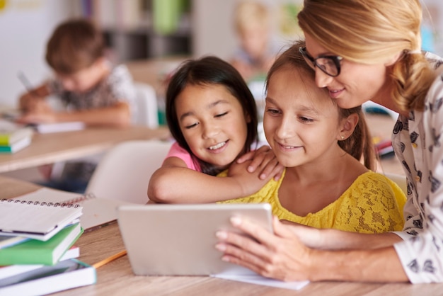 Teacher helping pupils with digital tablet