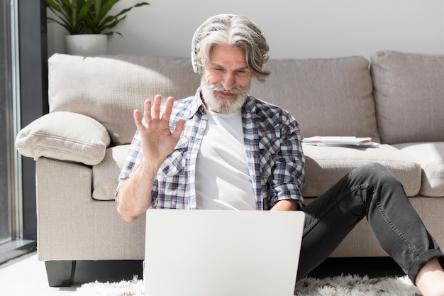 Teacher staying on floor waving at laptop