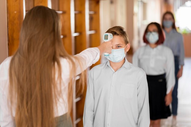 Teacher taking body temperature at school